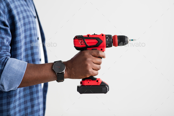 Home renovation, electric tool. Black man with smart watch holding electric drill, standing over