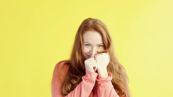 Studio portrait of beautiful young red-haired woman on yellow background