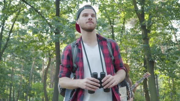 Confident Male Guide in Summer Forest with Group of Positive Young Tourists Strolling at the alt