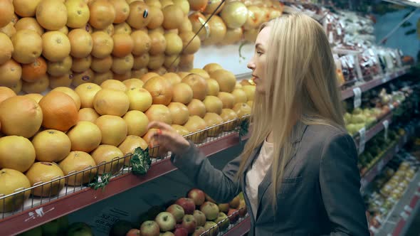 Young Woman Choosing Oranges in Grocery Store alt