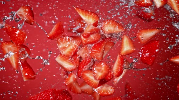 Super Slow Motion Shot of Fresh Strawberries and Water Side Collision on Red Background at 1000Fps. alt