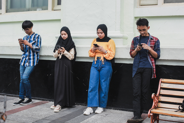 Group of people standing with distance and using smartphone together - Stock Photo - Images