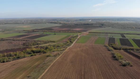 Aerial view of farmlands and roads, sunny, autumn day - tilt up, drone shot alt