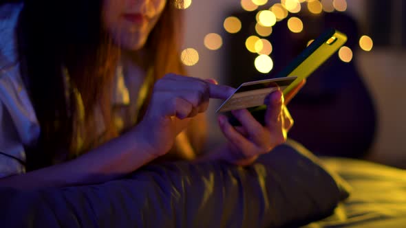 Close up shot of female hand holding credit card using smart phone for shopping online