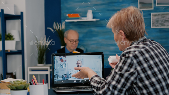 Retired woman talking at telehealth session by internet with young doctor - Stock Photo - Images