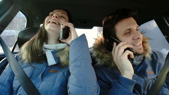 Man and Woman Speaking Their Cellphones and Laughing Sitting in Car