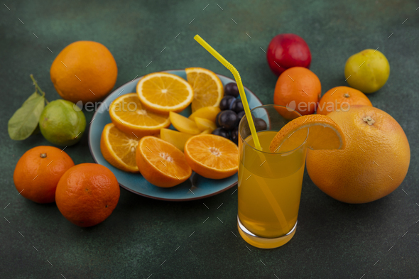 side view orange slices with cherry plum on a blue plate with orange juice grapefruit and lemon with