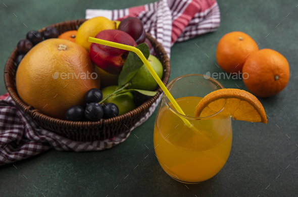 side view orange juice in a glass with grapefruit lime lemon peach cherry plum orange and plum in a
