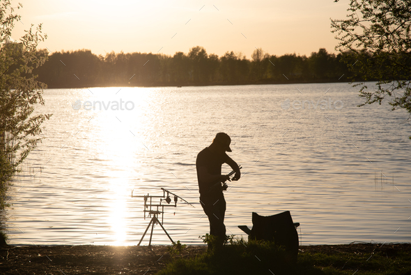 A fisherman silhouette fishing at sunset. Freshwater fishing