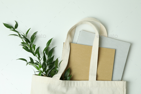 Eco bag with copybooks and twig on white background