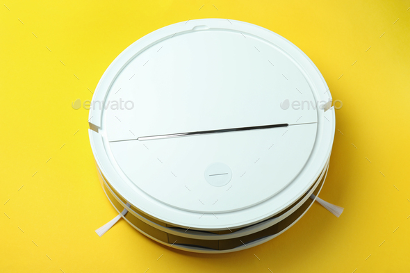 Modern robot vacuum cleaner on yellow background