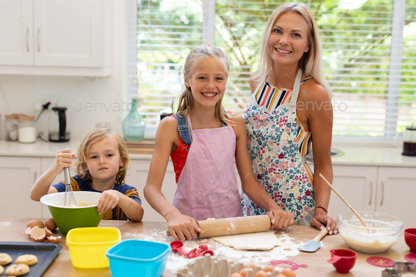 Beautiful stunning woman mother and daughter in aprons kitchen cooking in  the kitchen cookies and pasta noodles Stock Photo by ©marcink3333 169331726