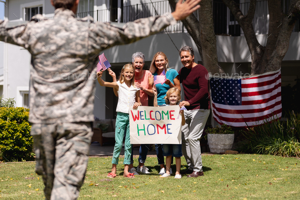 Caucasian soldier father and family meeting outside home with welcome sign and american flags