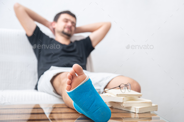 Close up man\'s broken leg in blue splint for treatment of injuries from ankle sprain at home.