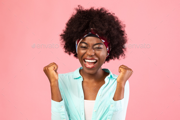 Emotional Bushy Black Woman Shaking Fists Celebrating Success, Pink Background