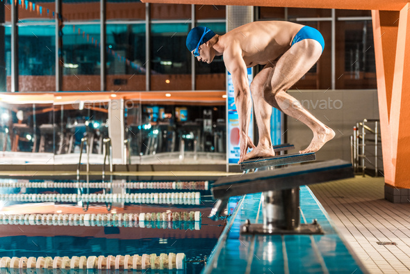 swimmer standing on diving board ready to jump into competition swimming pool