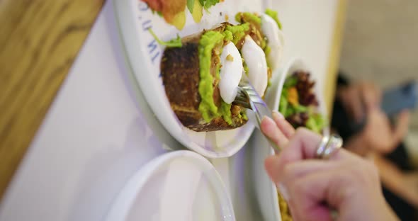 female hands pulling a sandwich with avocado, eggs and brown bread alt