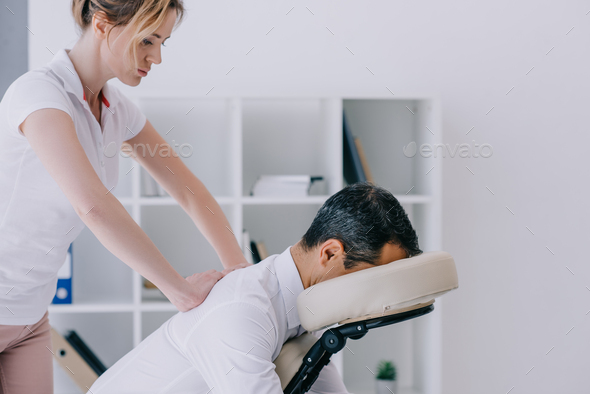side view of masseuse doing seated massage for businessman
