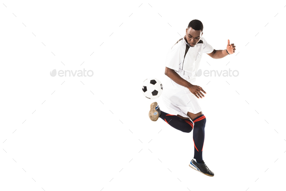 full length view of athletic african american soccer player kicking ball isolated on white