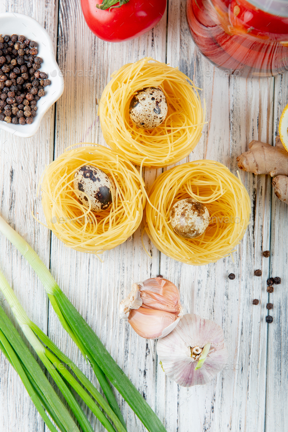 top view of vermicelli with mini eggs, black pepper grains, garlic, scallion on wooden background