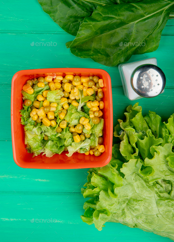 top view of bowl of yellow pea with sliced lettuce and spinach, salt, whole lettuce on green