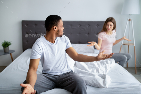 Young Interracial Couple Quarreling In Bedroom Being Angry Facing