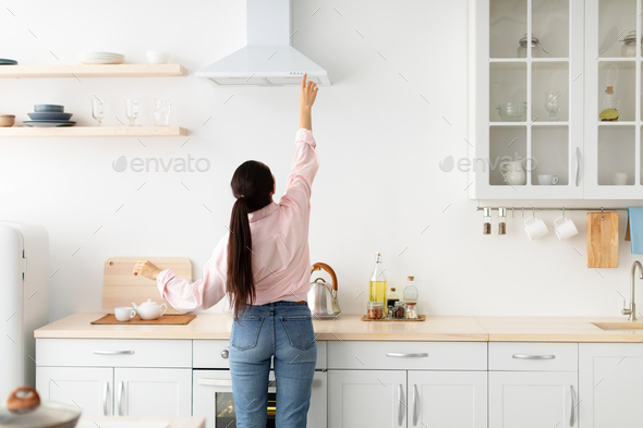 Woman select mode on cooking hood in kitchen - Stock Photo - Images