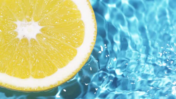 Macro Orange Fruit Slice and Blue Water Surface Texture with Ripples and Splash