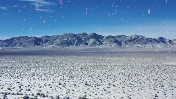 Mountain range and winter desert during snowfall, aerial drone view alt