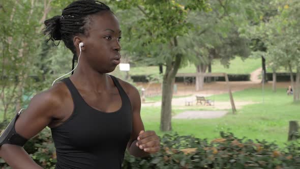 Attractive american african young woman running in the park. Training,strenght alt