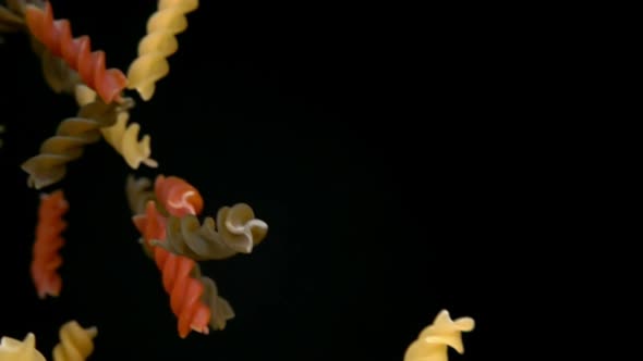 Closeup of the Colored Pasta Fusilli Falling Diagonally on the Black Background alt