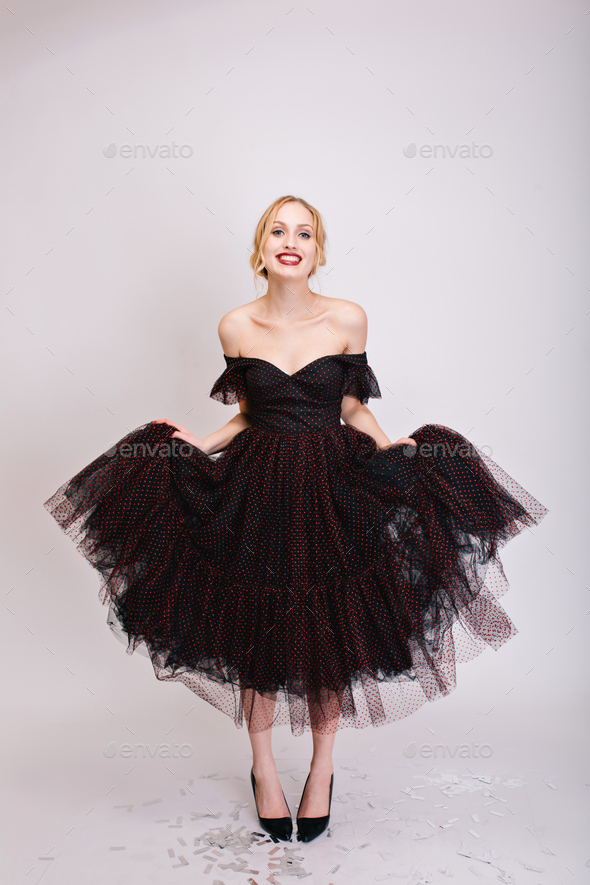 Closeup portrait of beautiful blonde trying on black fluffy dress, girl showing her nice cloth. Shoo