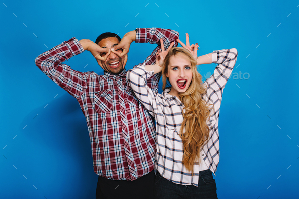 Excited funny young woman with long blonde hair having fun with handsome guy fooling around together