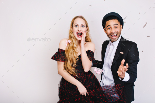 Portrait astonished young woman with long blonde hair in luxury dress with joyful handsome guy havin