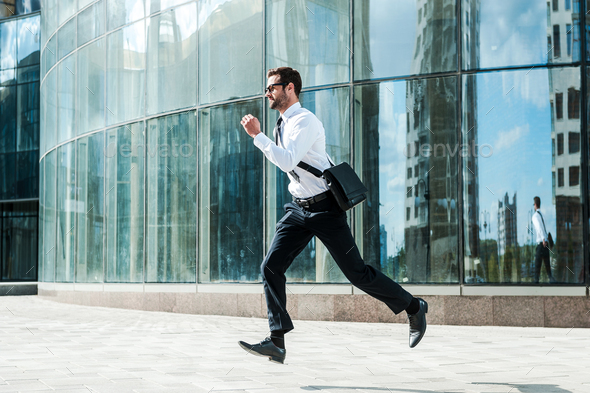 Hurrying to work. Full length of young businessman looking forward while running along the street