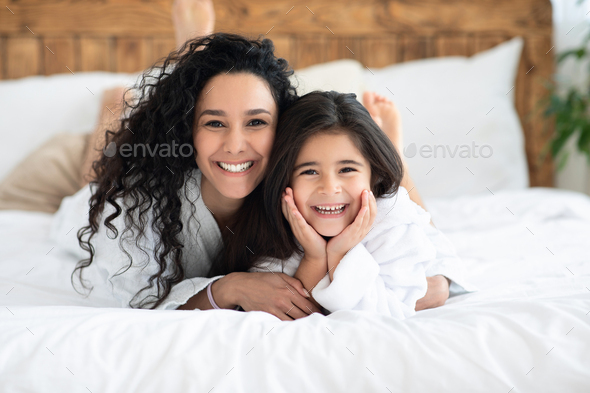 Cheerful caucasian mother and daughter bonding on bed