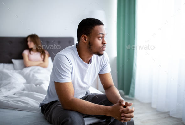 Relationship crisis. Young black man feeling upset after fight with his wife, sitting on bed at home