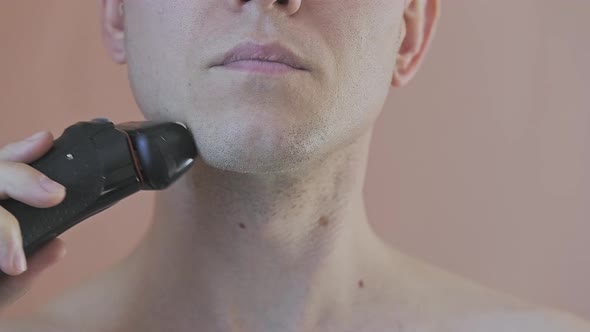 Front View of a Young Man Who is Shaving His Chin