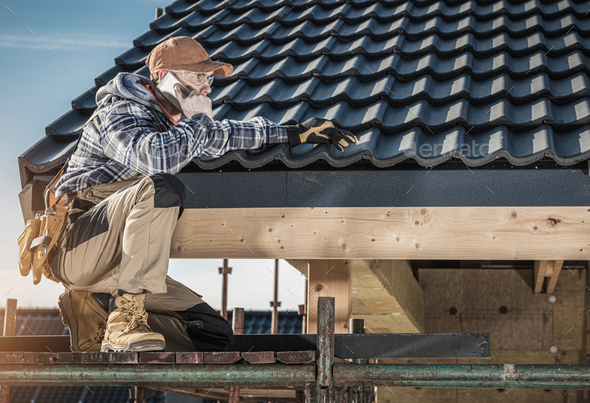 Roof Construction Worker Making Phone Call While Staying on Scaffolding. - Stock Photo - Images