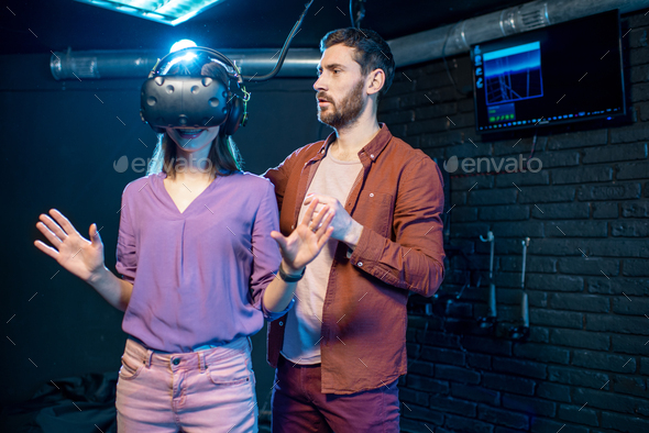 Woman trying virtual reality with man assistant