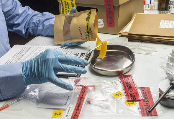 Police scientist holding rubber band evidence bag of a drug overdose case, conceptual image
