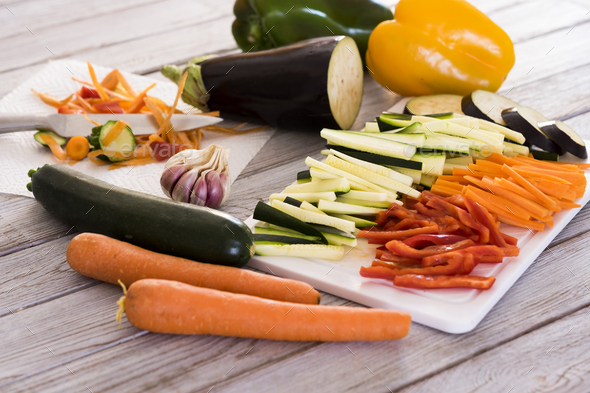 Fresh vegetables on a wooden table with a mix of sliced carrots, zucchini, eggplant and peppers - Stock Photo - Images
