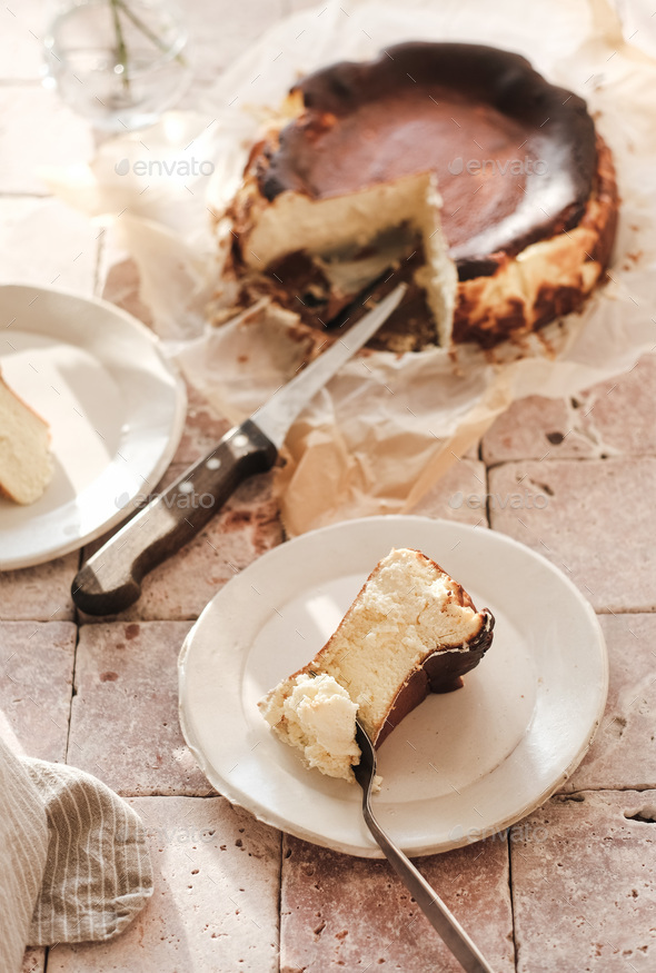Piece of Homemade San Sebastian burnt cheesecake on white plate - Stock Photo - Images