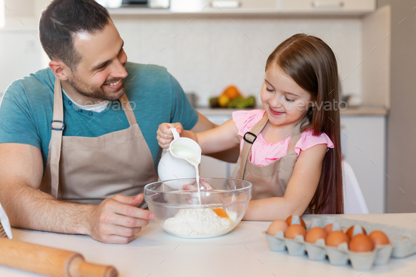 Daddy And Little Daughter Making Dough Baking Cake In Kitchen