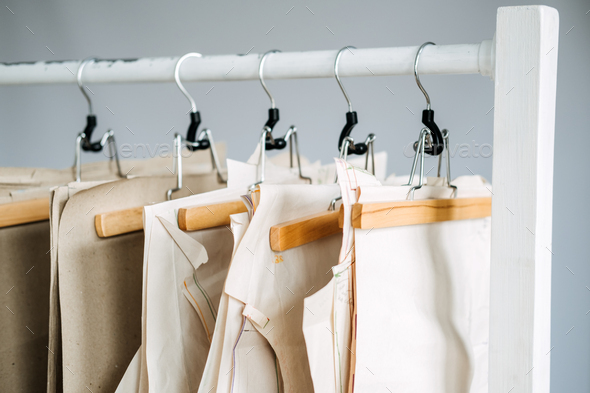 Many paper sewing patterns for different clothes hanging on the rack in  sewing factory background Stock Photo by IrynaKhabliuk