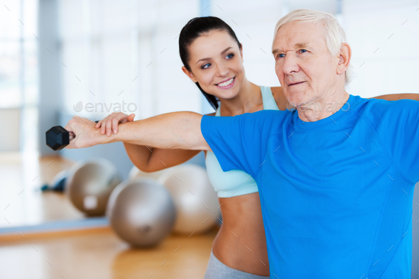 You are making progress! Confident female physical therapist working with senior man in health club