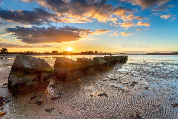 Beautiful sunset over old WWII tank traps in Bramble Bush Bay - Stock Photo - Images