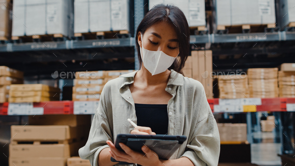 woman manager wear face mask looking for goods using digital tablet checking inventory. - Stock Photo - Images