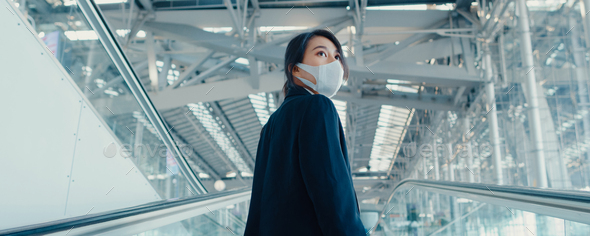 business girl wear face mask drag luggage stand on escalator look around walk to terminal.