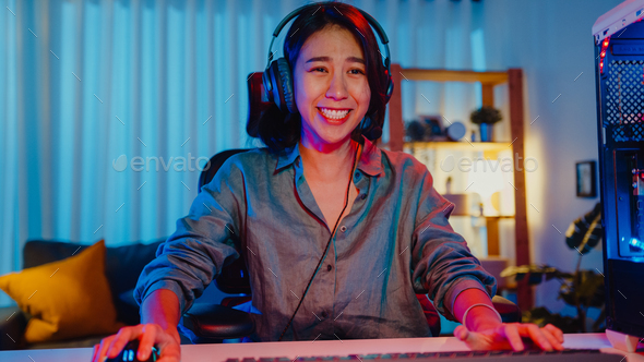 Happy asia girl gamer wear headphone competition play video game online  with smartphone. Stock Photo by Tirachard